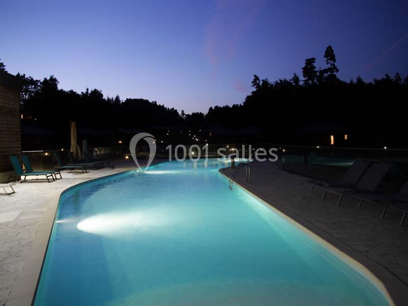 Location salle Meyrignac-l'Église (Corrèze) - Domaine des Monédières #16 Piscine éclairée en soirée, entourée de chaises longues et bordée par des arbres dans un cadre paisible.