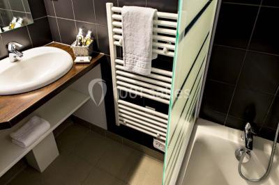 Miniature Location salle Meyrignac-l'Église (Corrèze) - Domaine des Monédières #24 Lavabo avec plan en bois, sèche-serviettes mural, douche avec paroi vitrée et carrelage sombre.