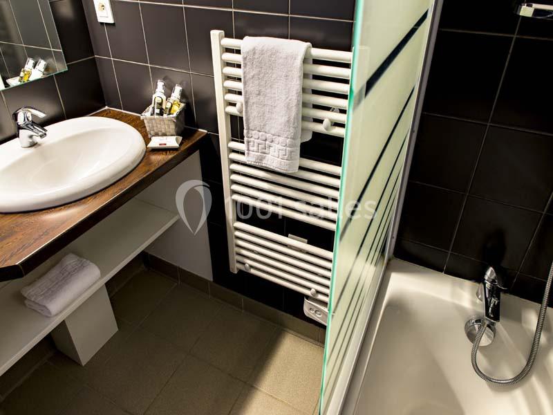 Location salle Meyrignac-l'Église (Corrèze) - Domaine des Monédières #24 Lavabo avec plan en bois, sèche-serviettes mural, douche avec paroi vitrée et carrelage sombre.