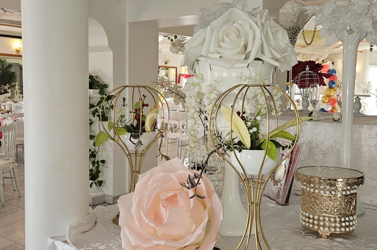 Salle de réception décorée avec des fleurs, des tables dressées et des éléments décoratifs élégants.