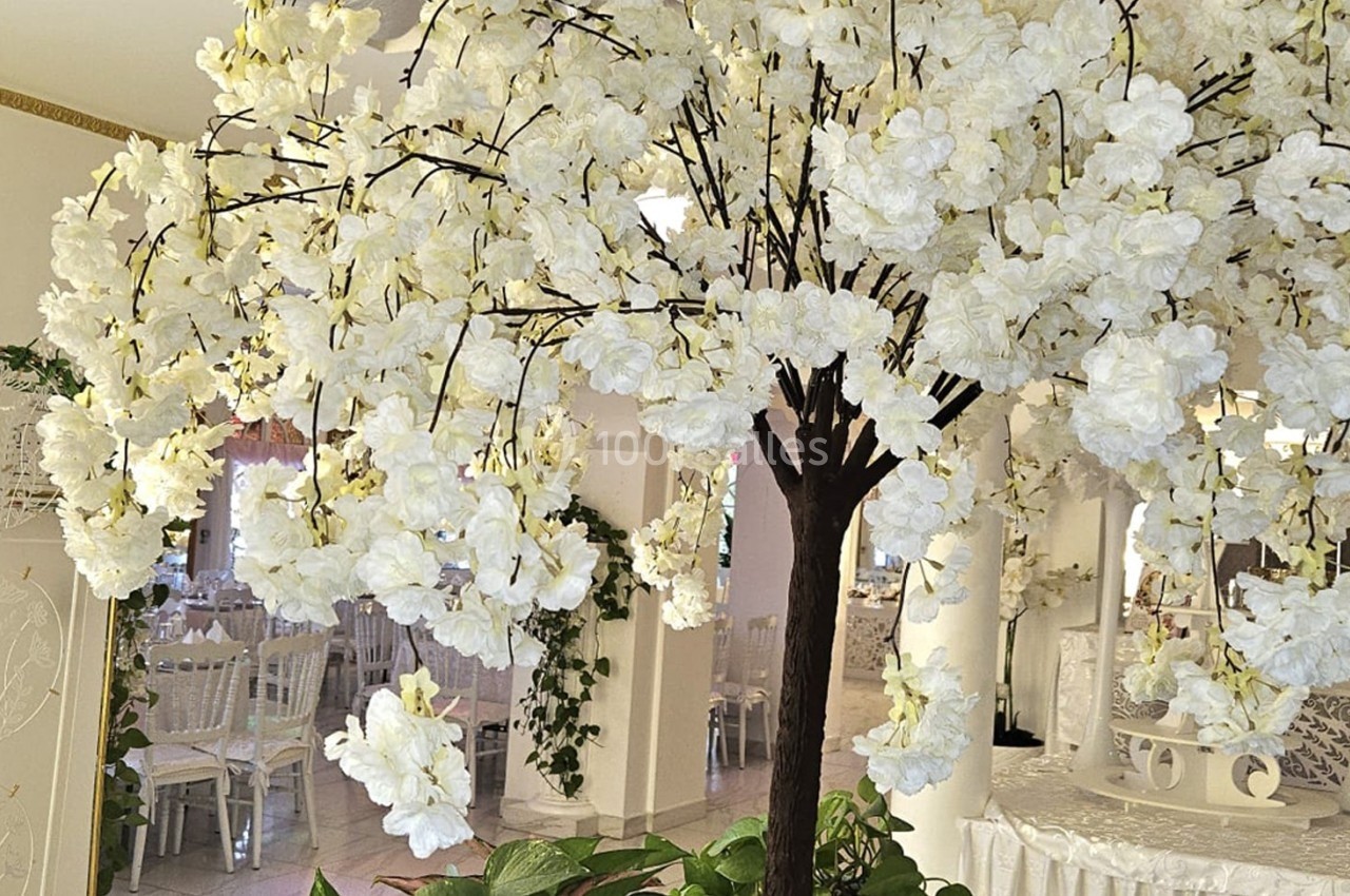 Arbre décoratif aux fleurs blanches dans une salle de réception lumineuse et élégamment aménagée.