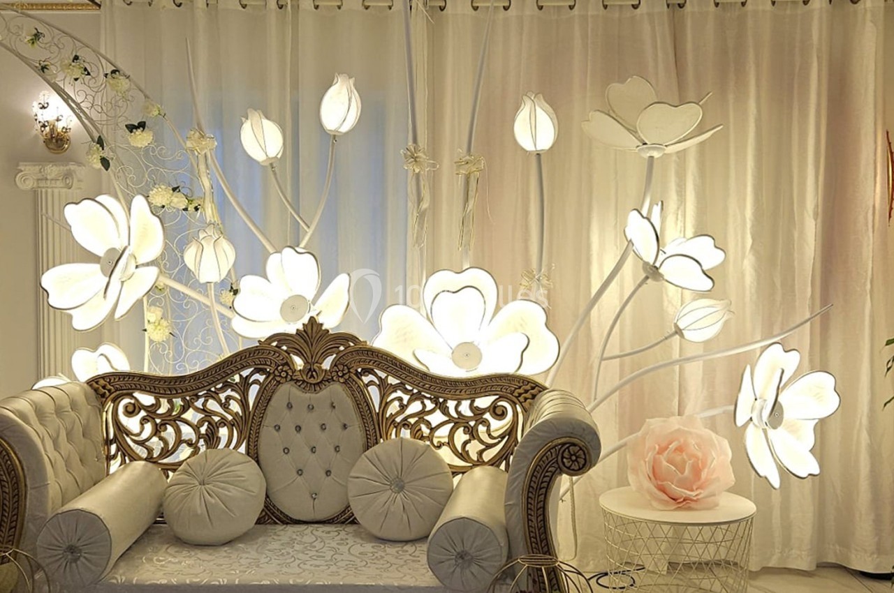 Canapé décoratif devant un rideau lumineux orné de fleurs blanches, dans un cadre élégant et raffiné.