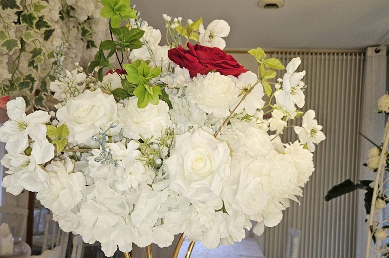 Bouquet de fleurs blanches et rouges au centre d'une salle décorée pour un événement festif.