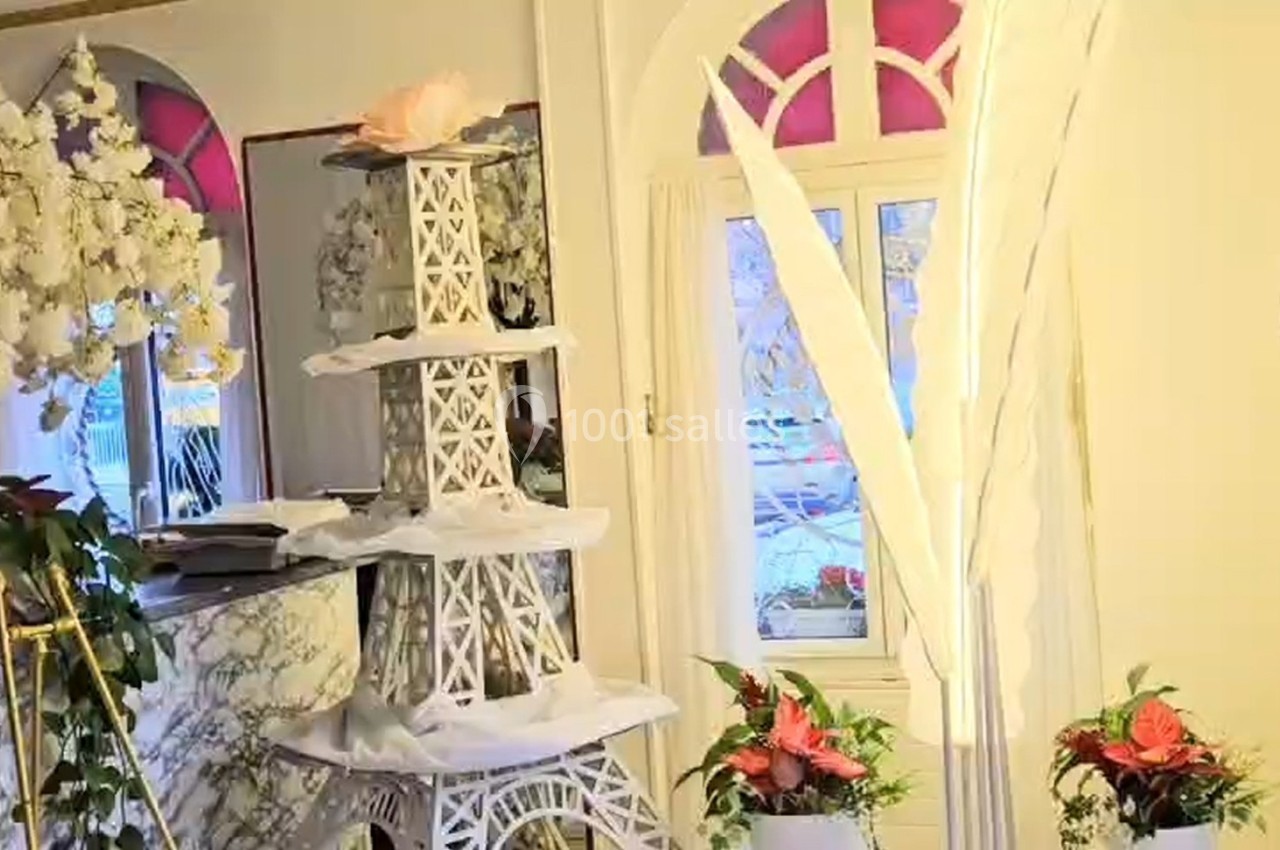 Décoration intérieure avec une tour Eiffel blanche ornée de fleurs, entourée de plantes et d'éléments floraux.