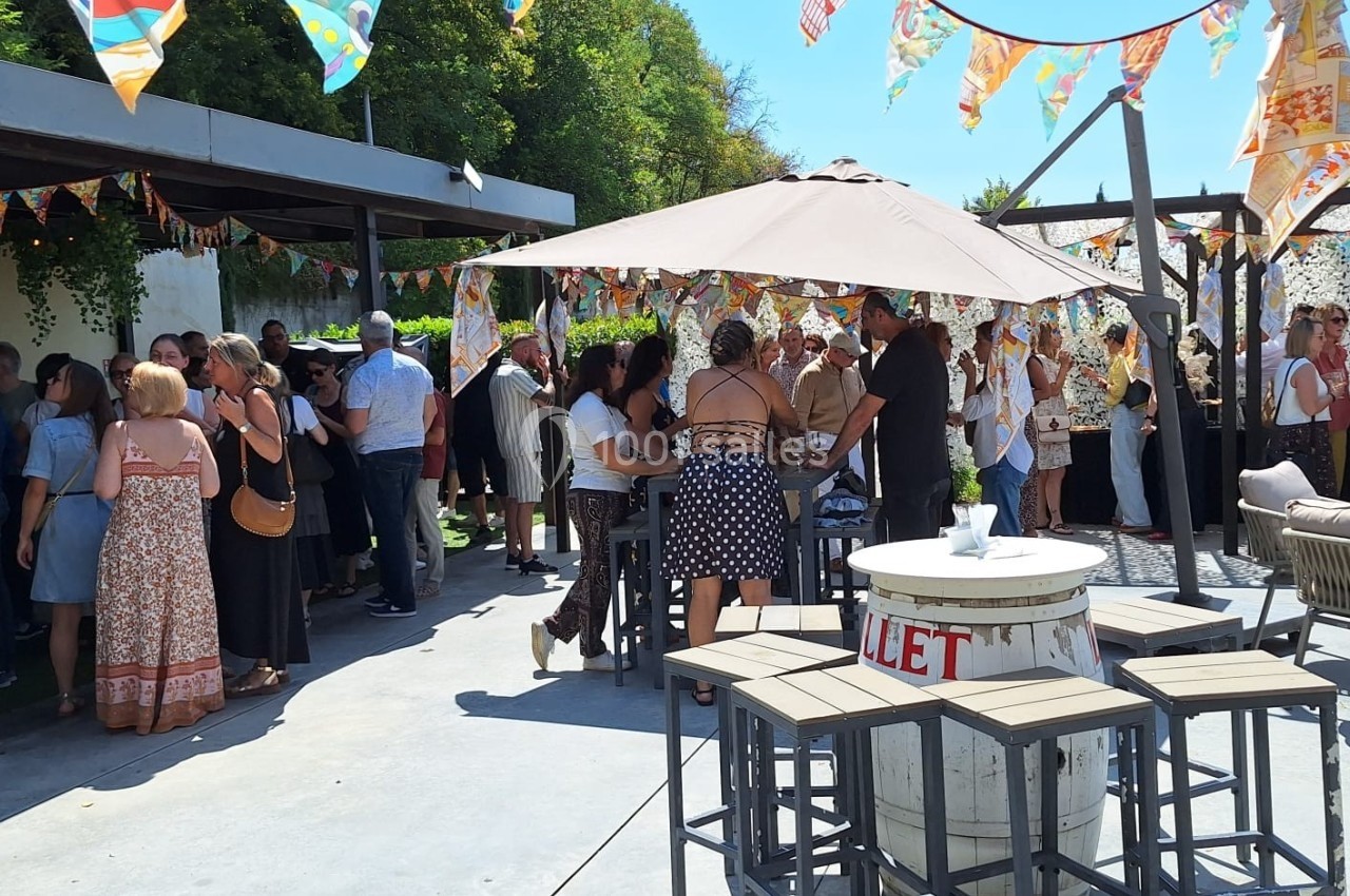 Groupe de personnes rassemblées dans une cour extérieure décorée de guirlandes colorées lors d'un événement festif.