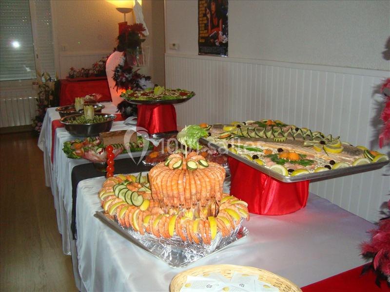 Buffet garni de plats variés, incluant fruits de mer, légumes et charcuteries, disposés sur des nappes blanches et rouges.