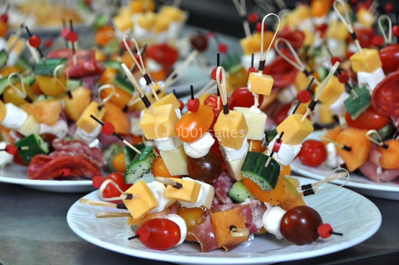 Assortiment de brochettes apéritives colorées avec légumes, fromages, charcuteries et fruits, disposées sur des assiettes.