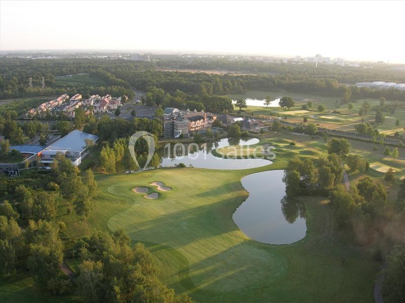 Vue aérienne d'un terrain de golf avec des étangs, des greens et des bâtiments entourés de végétation.