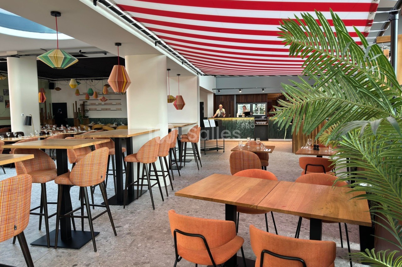 Salle de restaurant moderne avec tables en bois, chaises orange, plantes et un plafond à rayures rouges et blanches.
