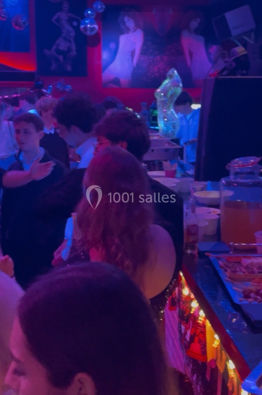 Des personnes dans une ambiance festive, rassemblées autour d'un buffet dans une salle éclairée par des lumières colorées.