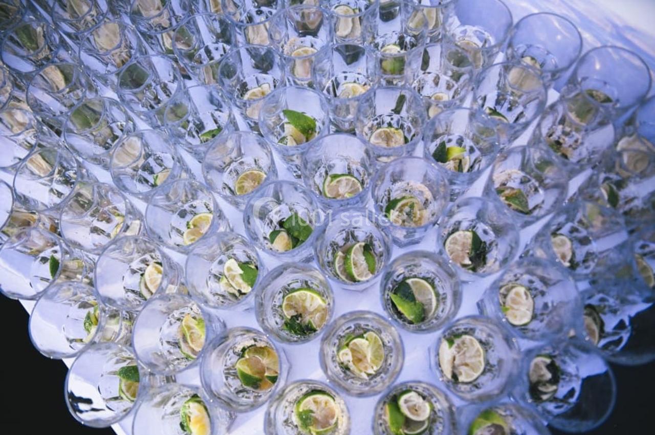 Verres remplis d'eau ou de cocktails, garnis de tranches de citron vert et disposés en motif circulaire.