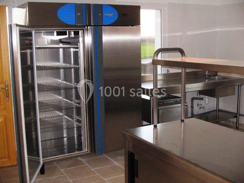 Cuisine professionnelle avec réfrigérateur ouvert, plan de travail en inox et équipements en acier inoxydable.