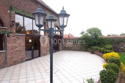 Miniature Location salle Belœil (Hainaut) - La Grange Aux Artistes #23 Jardin ensoleillé avec des palmiers au premier plan, pelouse verte et tables hautes recouvertes de nappes noires en arrière…