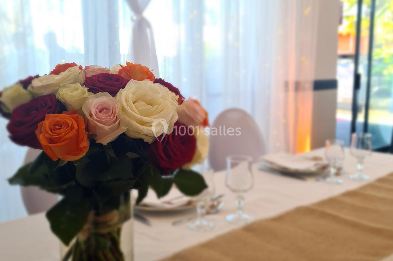 Bouquet de roses colorées sur une table décorée avec nappe en toile de jute dans une salle lumineuse.