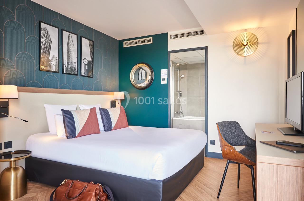 Chambre d'hôtel moderne avec lit double, bureau, télévision, salle de bain attenante et décoration contemporaine.
