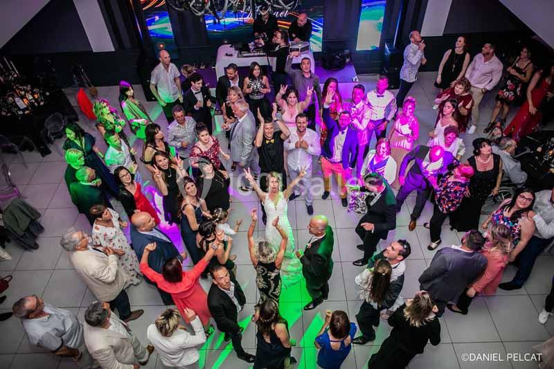 Vue aérienne d'un groupe de personnes dansant et socialisant lors d'une fête dans une salle éclairée par des lumières…