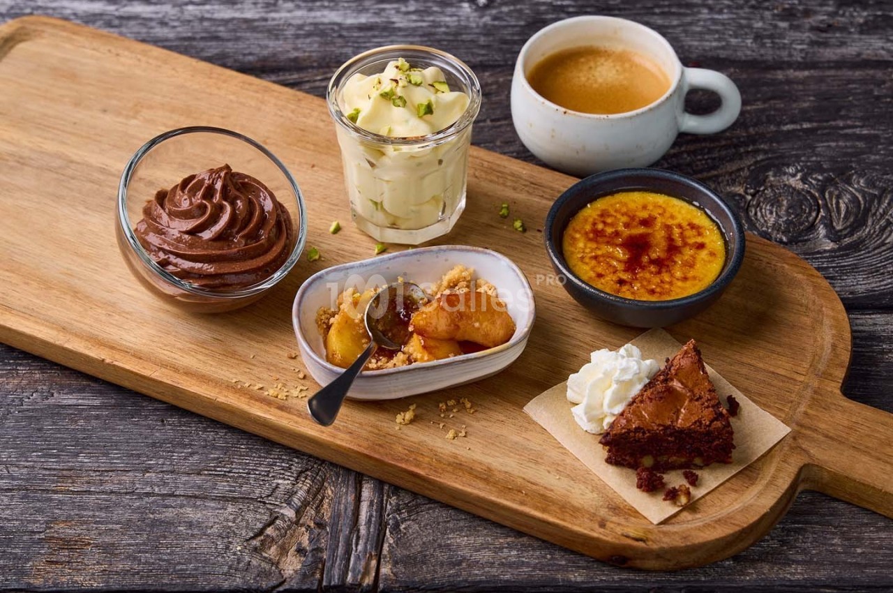 Plateau en bois avec mousse au chocolat, tiramisu, crème brûlée, crumble aux pommes, brownie et tasse de café.