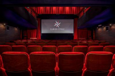 Façade du cinéma ’Club de l'Étoile’ avec une entrée vitrée et des voitures stationnées devant.