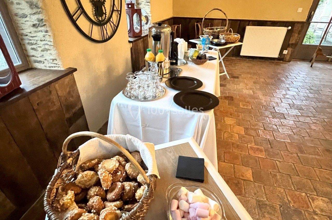Buffet avec viennoiseries, boissons chaudes, jus d’orange et guimauves dans une salle au style rustique.