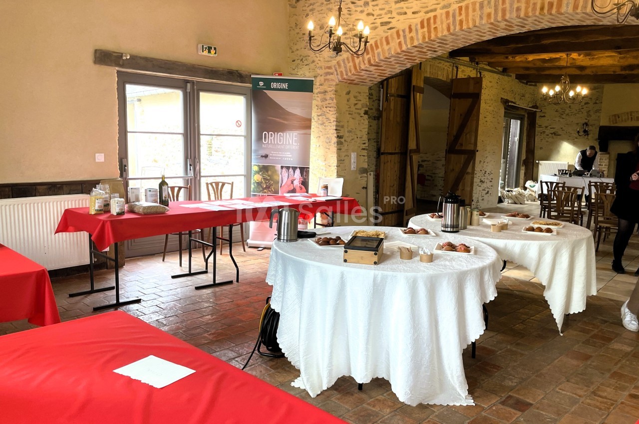 Salle avec des tables recouvertes de nappes rouges et blanches, disposées pour un buffet dans un cadre rustique.