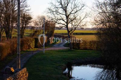 Miniature Location salle Menus (Orne) - Gîte de La Bretillière #13 Chemin de campagne bordé de poteaux électriques et clôtures, traversant un paysage rural sous un ciel sombre.