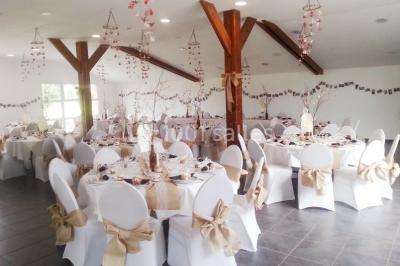 Miniature Location salle Saint-Pôtan (Côtes-d'Armor) - La Métairie de la Barre #5 Table ronde décorée pour un événement, avec nappes beige, chaises blanches ornées de tissu orange et centre de table floral.