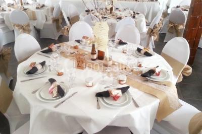 Miniature Location salle Saint-Pôtan (Côtes-d'Armor) - La Métairie de la Barre #6 Table ronde décorée pour un événement, avec nappes beige, chaises blanches ornées de tissu orange et centre de table floral.