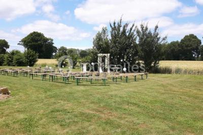 Miniature Location salle Saint-Pôtan (Côtes-d'Armor) - La Métairie de la Barre #9 Table ronde décorée pour un événement, avec nappes beige, chaises blanches ornées de tissu orange et centre de table floral.