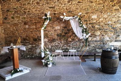 Miniature Location salle Saint-Pôtan (Côtes-d'Armor) - La Métairie de la Barre #4 Table ronde décorée pour un événement, avec nappes beige, chaises blanches ornées de tissu orange et centre de table floral.