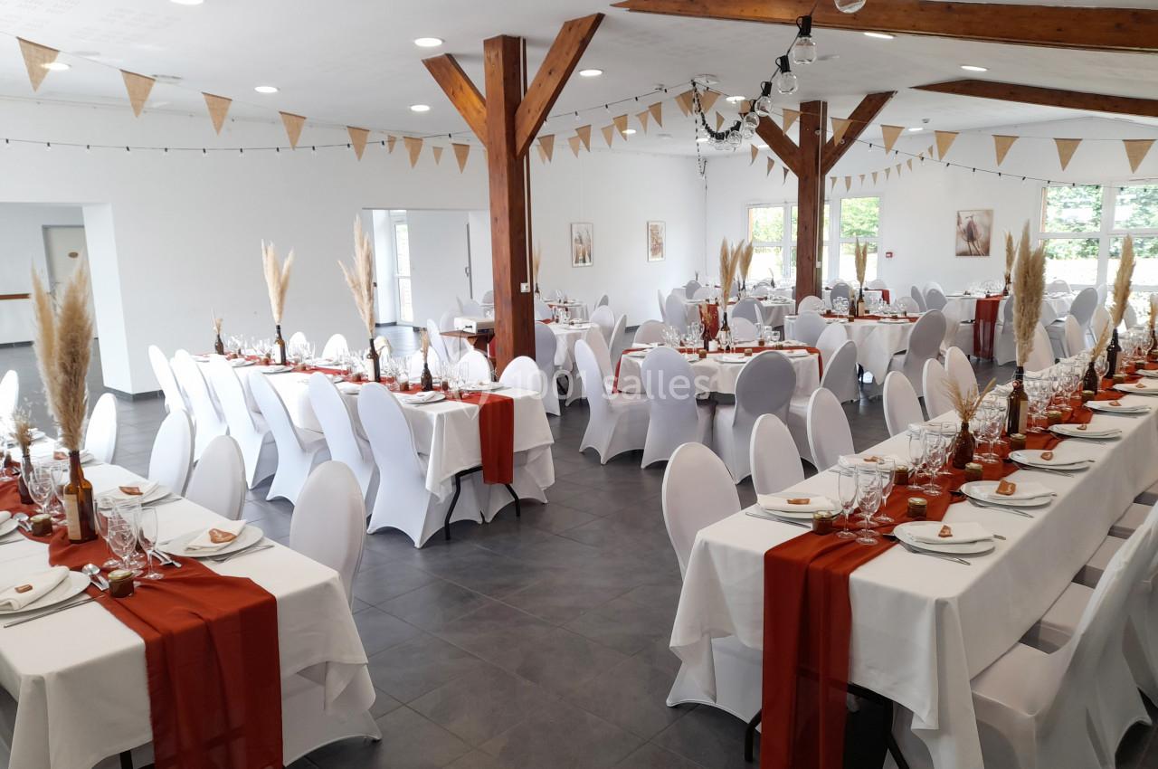 Location salle Saint-Pôtan (Côtes-d'Armor) - La Métairie de la Barre #14 Salle de réception décorée pour un événement, avec tables dressées, nappes blanches et chemins de table rouges.