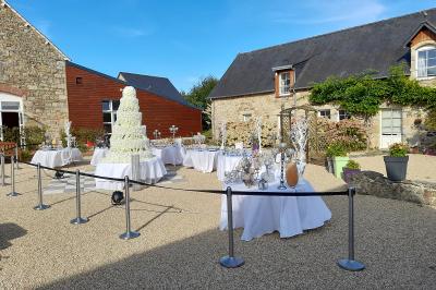 Miniature Location salle Saint-Pôtan (Côtes-d'Armor) - La Métairie de la Barre #3 Table ronde décorée pour un événement, avec nappes beige, chaises blanches ornées de tissu orange et centre de table floral.
