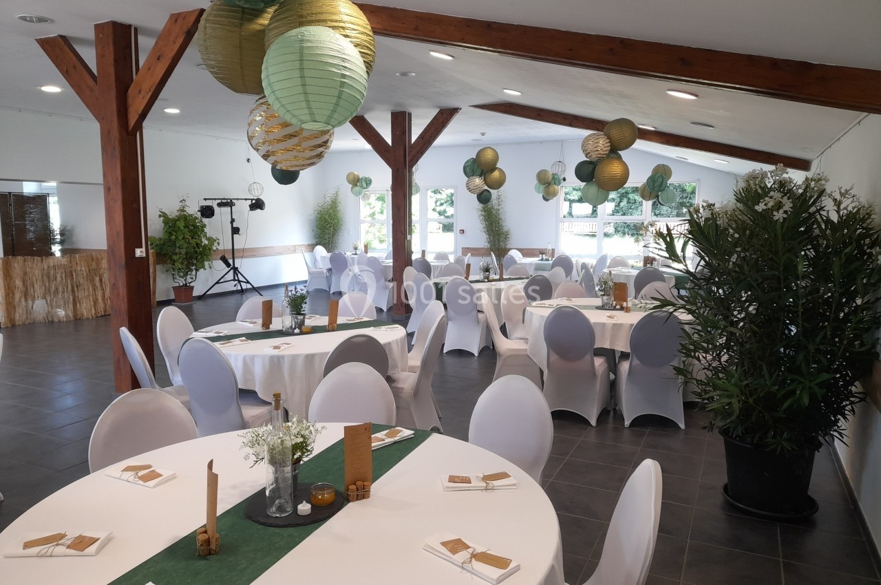Location salle Saint-Pôtan (Côtes-d'Armor) - La Métairie de la Barre #25 Salle de réception décorée avec des tables rondes, nappes blanches, lanternes suspendues et plantes vertes.
