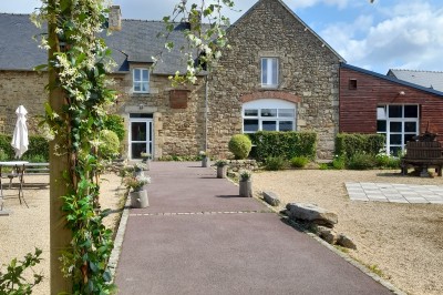 Miniature Location salle Saint-Pôtan (Côtes-d'Armor) - La Métairie de la Barre #26 Table ronde décorée pour un événement, avec nappes beige, chaises blanches ornées de tissu orange et centre de table floral.
