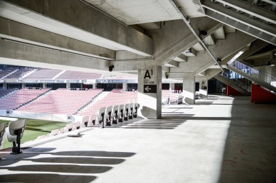 Salle lumineuse avec fauteuils rouges, table basse en verre, écran mural et baie vitrée donnant sur l'extérieur.