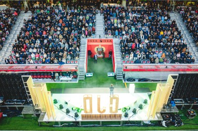 Salle lumineuse avec fauteuils rouges, table basse en verre, écran mural et baie vitrée donnant sur l'extérieur.