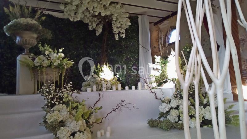 Décoration florale blanche et verte avec bougies et branches dans un espace intérieur au style naturel et élégant.