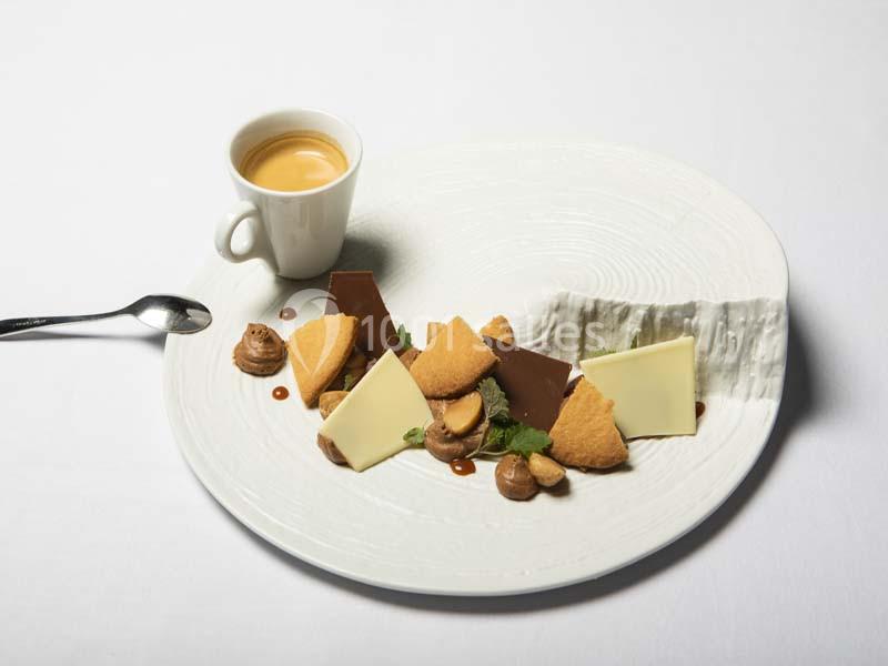 Assiette de dessert composée de morceaux de chocolat, biscuits, mousse et menthe, accompagnée d'un expresso.