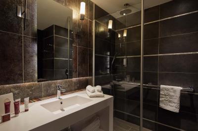 Miniature Location salle Le Touquet-Paris-Plage (Pas-de-Calais) - Le Grand Hôtel Le Touquet #21 Salle de bain moderne avec lavabo blanc, douche vitrée, murs carrelés sombres et éclairage chaleureux.
