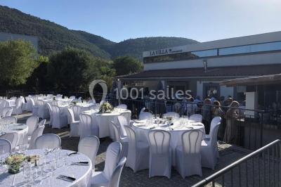 Table de réception élégamment dressée avec nappes blanches, serviettes décorées, verres et couverts alignés.