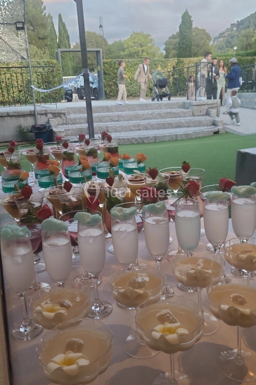 Desserts variés présentés sur une table, avec une vue sur un jardin et des passants en arrière-plan.