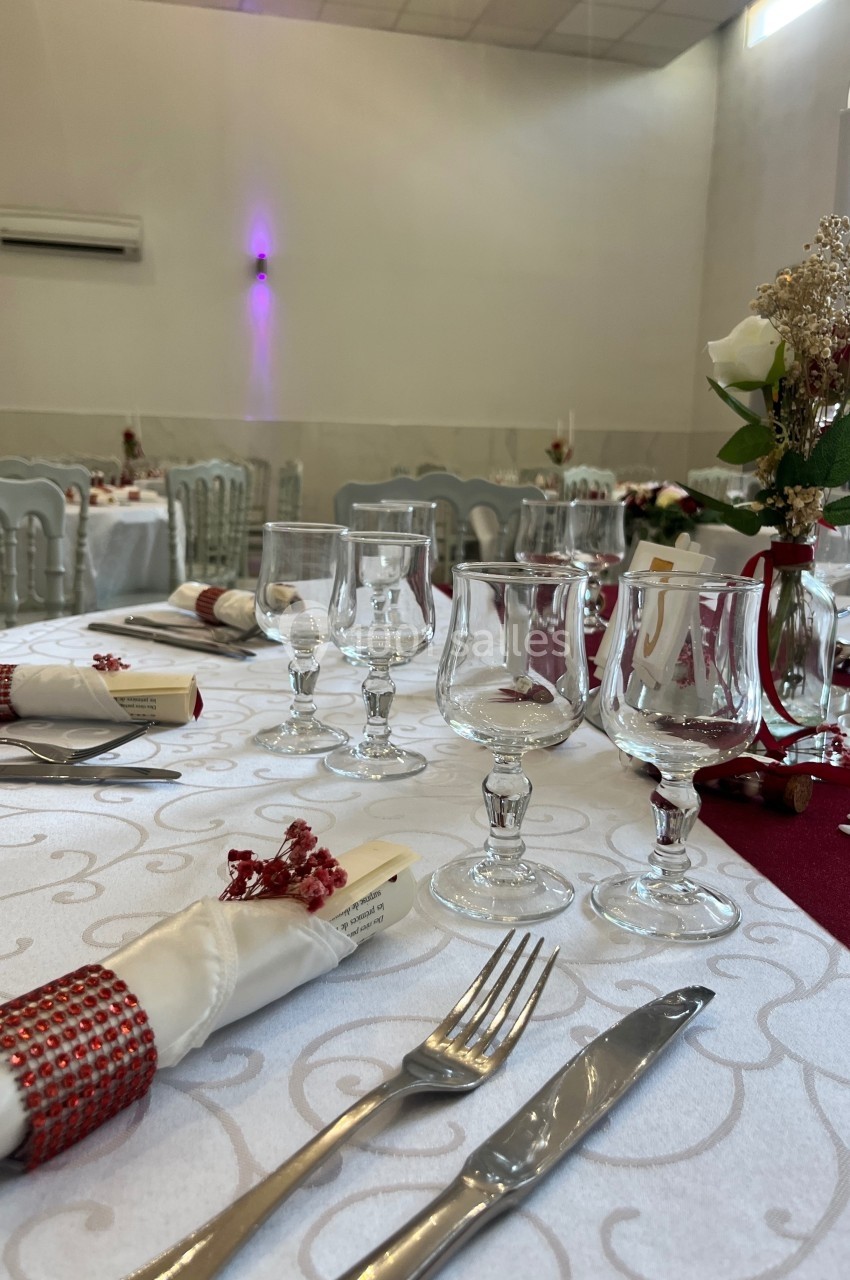 Table de réception élégamment dressée avec nappes blanches, serviettes décorées, verres et couverts alignés.