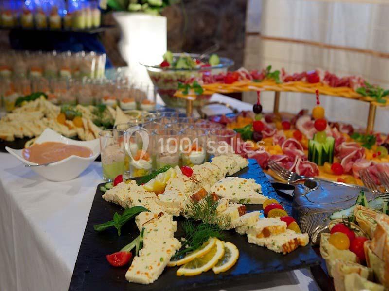 Plateau de fromages et charcuteries avec décorations de fruits et herbes, entouré de verrines et autres mets.