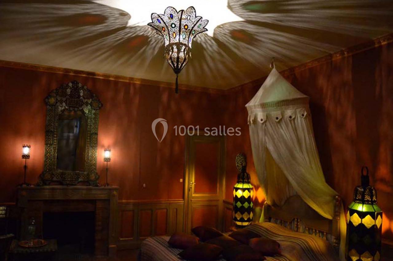 Chambre décorée dans un style oriental avec un lit à baldaquin, des lampes colorées et un éclairage tamisé.