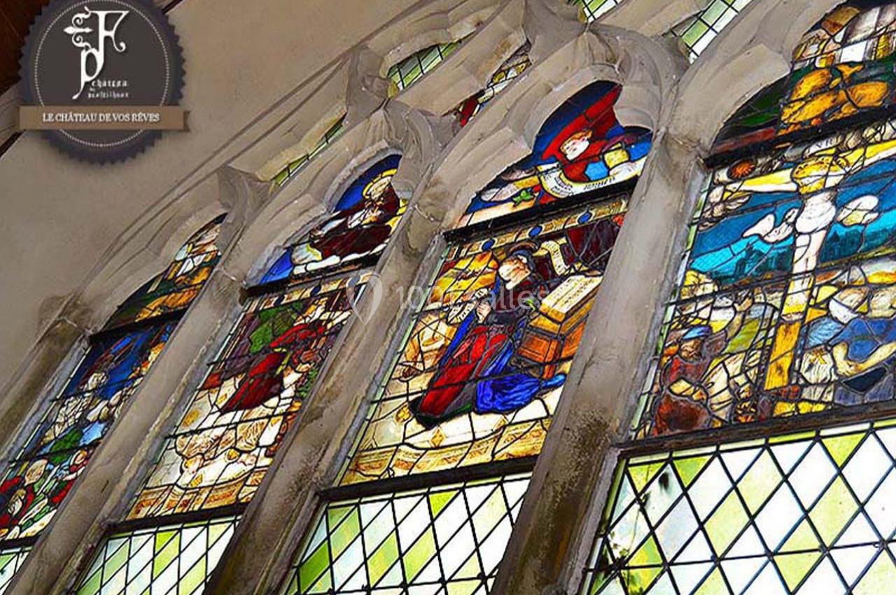 Vitraux colorés représentant des scènes religieuses dans une église, encadrés par des arches en pierre.