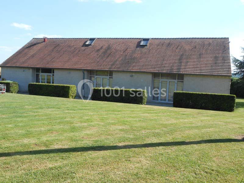 Maison à un étage avec toit en tuiles, grandes fenêtres et pelouse bien entretenue au premier plan.