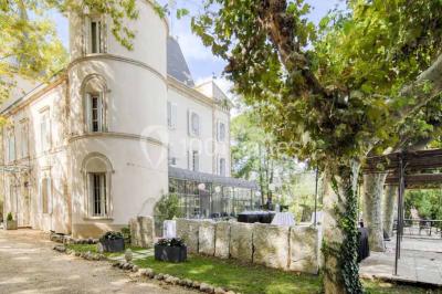 Salle de bain avec baignoire encastrée, lavabo sur meuble en marbre beige et fenêtre laissant entrer la lumière naturelle.