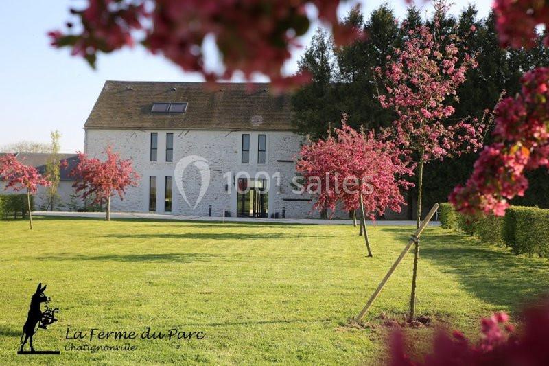 Bâtiment en pierre entouré d'un jardin verdoyant avec des arbres en fleurs roses au premier plan.