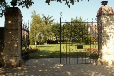Jardin verdoyant avec pelouse bien entretenue, arbres et arbustes sous un ciel bleu dégagé.