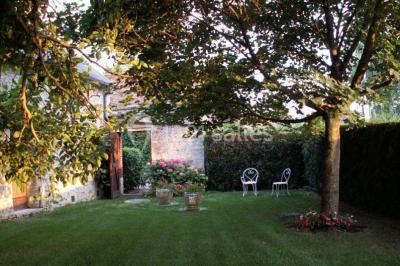 Jardin verdoyant avec pelouse bien entretenue, arbres et arbustes sous un ciel bleu dégagé.