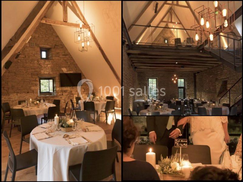 Salle de réception en pierre avec poutres apparentes, tables décorées pour un événement, ambiance chaleureuse.